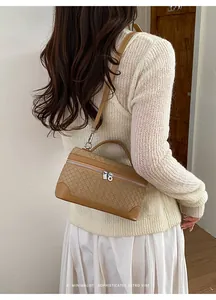 Détail d'un sac à main marron à texture tressée avec ferrures argentées et style épuré