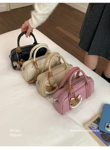 Detail of Boston bags in black, white, oat, and pink with horse charm and pebble texture