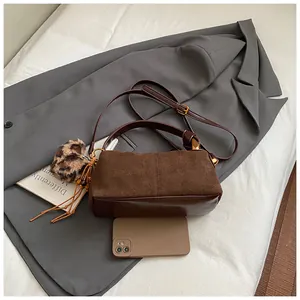 Detail view of vintage brown bag with leopard plush charm and size reference with a phone