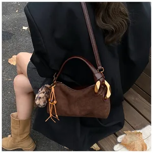 Detail of vintage brown suede pillow bag with leopard pompom and gold ring accent