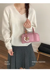 Pink Boston bag with wooden rocking horse charm shown in a lifestyle fashion setting