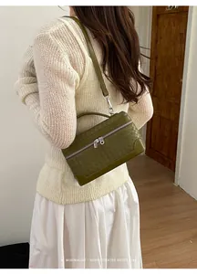 Détail de la texture en cuir tressé vert olive et du zip argenté du mini sac à main