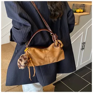 Brown suede pillow bag with gold chain and leopard print pom-pom charm detail