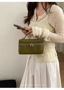 Détail d'un sac à main tressé vert foncé avec doubles fermetures éclair et poignée