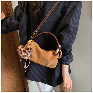 Detail of vintage brown suede crossbody bag with gold chain link and leopard heart charm