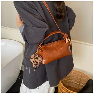 Brown vintage doctor style handbag with leopard print charm worn by a model