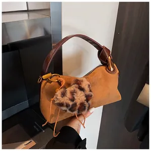 Detail of retro brown suede pillow bag with a plush leopard print heart charm and gold hardware