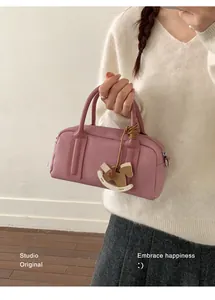 Close-up of pink Boston bag with lychee grain texture and a wooden rocking horse charm