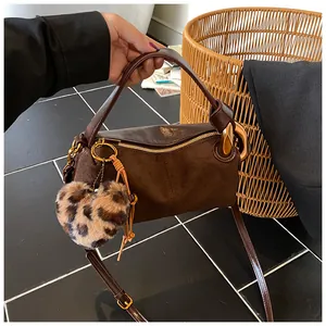 Detailed view of deep brown leather bag with golden hardware and leopard print heart charm