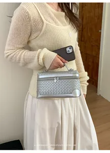 Détail du sac cosmétique tressé argenté avec coins en métal et double fermeture