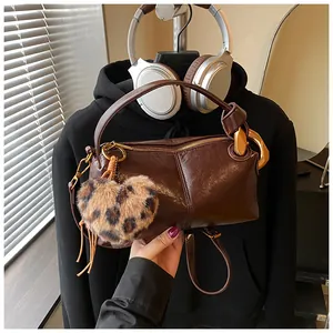 Close-up of dark brown glossy pillow bag with leopard heart charm and gold hardware