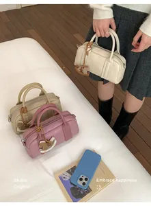 Detailed view of mini Boston bags in cream and pink colors with horse charms