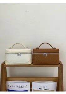Détail du tissage sur sacs à main beige et marron avec fermetures éclair argentées