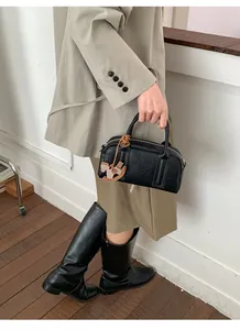 Close-up of black Boston bag with textured leather and a brown horse charm detail