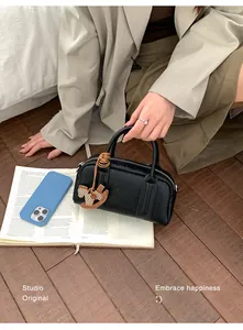 Top view of a black pebble leather Boston bag with a wooden horse charm on a wooden floor