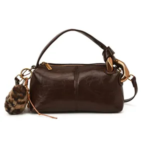 Vintage brown leather boston handbag with a metallic chain strap and fuzzy pompom accessory