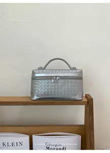 Gros plan sur la texture en cuir tressé argenté et le fermoir verrouillé de ce sac