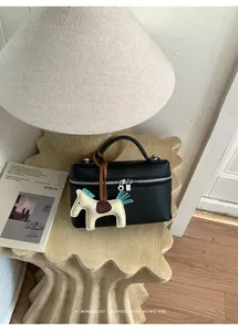 Détail du sac à main en cuir grainé noir avec fermetures éclair et breloque cheval