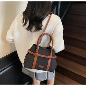 Vista posteriore di una borsa in tela nera con finiture in pelle marrone indossata