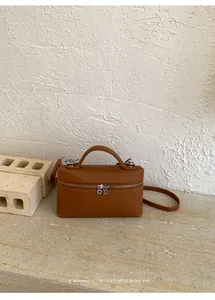 Vue détaillée de la texture du cuir marron et de la fermeture éclair argentée de ce sac carré