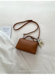 Détail d'un sac à main marron avec motif lychee et charm cheval blanc sur tissu doux