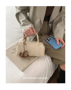 Detail of cream Boston bag with leather strap and wooden horse charm in lifestyle setting
