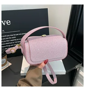 Détail d'un sac boîte en tweed rose clair avec boucle ronde dorée et texture pailletée