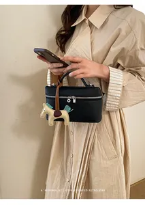 Détail du sac à main noir en cuir grainé avec accessoire chic de breloque de cheval