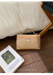 Détail d'un sac à main tissé marron clair avec double fermeture éclair sur bois