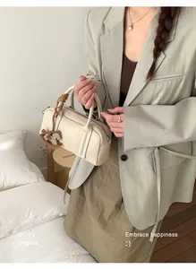 Detail of a creamy white Boston bag featuring a playful leather pony charm attachment
