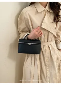 Détail d'un mini sac à main en cuir grainé noir avec ferrures argentées sur une tenue beige