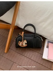 Detail of black pebbled leather Boston bag with decorative horse charm in natural lighting