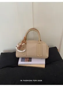 Close-up of beige Boston bag with horse pendant on vintage books for texture detail