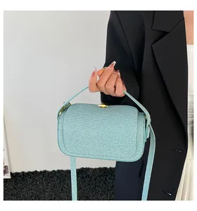 Détail d'un sac à main tissé bleu clair avec fermoir doré et bandoulière