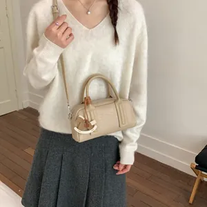 Minimalist beige Boston crossbody bag with a wooden horse charm on a model