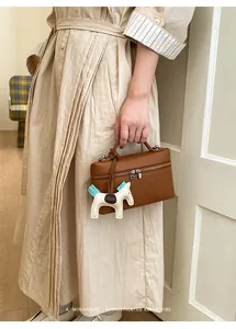Détail d'un sac à main en cuir marron foncé avec un pendentif cheval élégant en accessoire