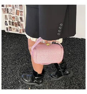 Petit sac à main rose scintillant porté par un mannequin montrant texture et boucle dorée