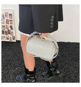 Détail du sac à main argenté scintillant avec fermoir coquillage doré et poignée
