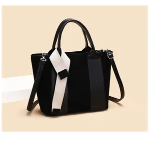 Detail of matte black tote bag featuring cream webbing and smooth leather trim finish