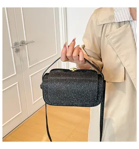 Détail du sac à main noir pailleté avec poignée incurvée et longue bandoulière