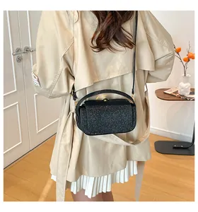 Détail du sac bandoulière noir scintillant avec boucle dorée et texture sur un mannequin