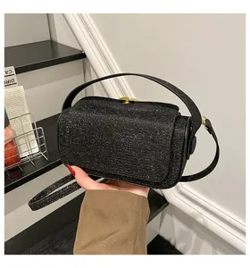 Gros plan d'un mini sac bandoulière à paillettes noires avec des détails dorés