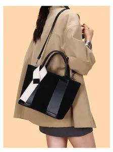 Detail of black suede tote bag with decorative scarf and detachable shoulder strap on model