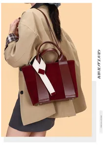 Detail of burgundy leather tote bag with white fabric strap on a beige coat