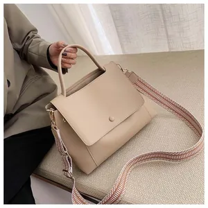 Detail of apricot crossbody bag featuring a stylish black and white geometric wide strap