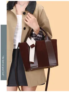 Close-up of a matte suede tote bag with leather patchwork and decorative webbing strap