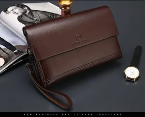 Detail van donkerbruine herenclutch van korrelig leer met polsband en metalen rits