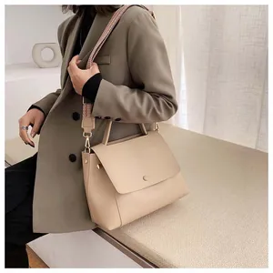 Detailed view of beige shoulder bag featuring a wide jacquard woven strap and round buckle