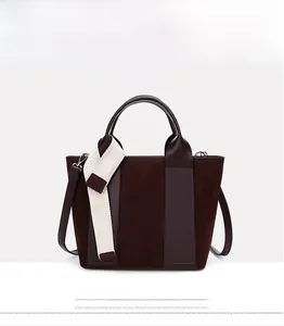 Detail of dark brown tote bag showing matte texture and woven cream strap accent