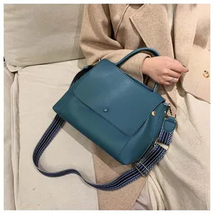 Teal leather handbag featuring a stylish geometric patterned wide fabric shoulder strap